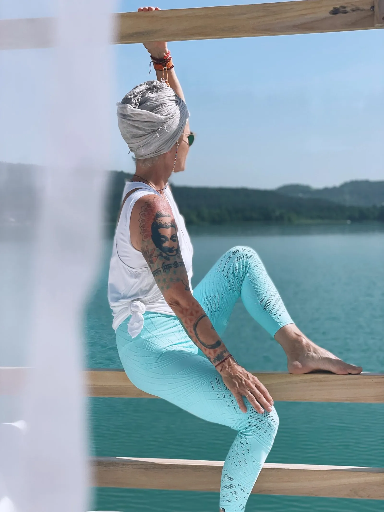 Frau mit Turban sitzt auf einem Holzgeländer am See